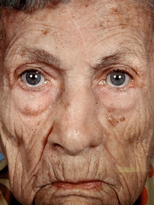 An old woman with blue eyes and a wrinkled face.