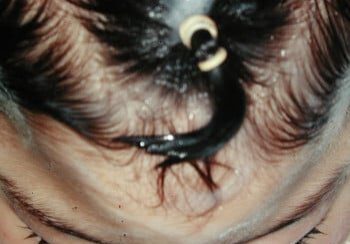 A woman 's face with black hair and long eyelashes.