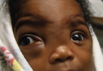 A close up of a baby with a towel on its head